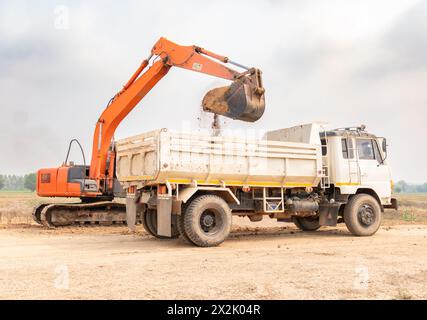 Baustelle mit Backho. Bagger beladen einen Lkw mit Boden Stockfoto