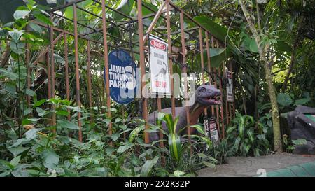 Dinosaurier-Statue in einem Käfig mit gefährlicher Schrift und Waldhintergrund im Dino Park Jatim Park 3 Batu Stockfoto
