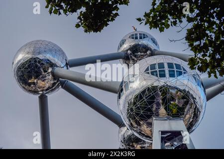 Nahaufnahme des Atomiums in Brüssel mit seinen metallischen Kugeln und Verbindungsröhren, umrahmt von grünem Laub. Stockfoto