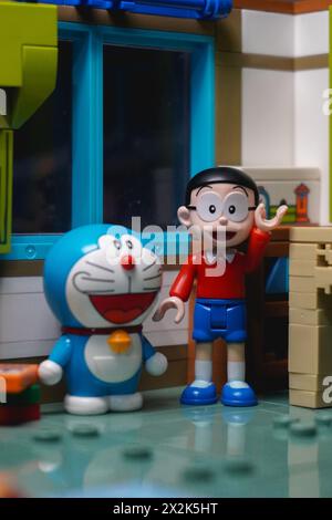 Die Figur von Nobita hebt eine seiner Hände und steht mit Doraemon in seinem Zimmer mit einem glücklichen Gesicht Stockfoto
