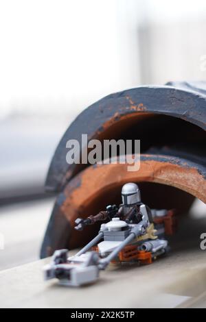 Die LEGO Minifiguren Mandalorian und Baby Yoda (Grogu) gehen durch einen dunklen Tunnel mit verschwommenem Hintergrund Stockfoto