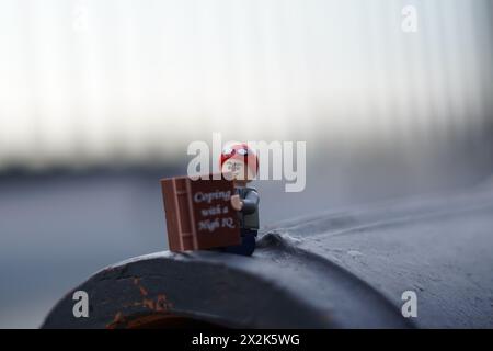 LEGO Minifigur Peter Parker sitzt und liest ein Buch mit verschwommenem Hintergrund und Kopierraum Stockfoto