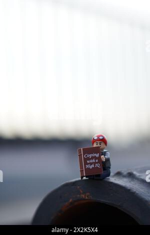 LEGO Minifigur Peter Parker sitzt und liest ein Buch mit verschwommenem Hintergrund und Kopierraum Stockfoto