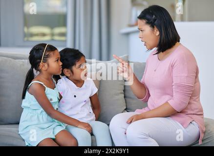 Mutter, zeigende und schimpfende Kinder im Haus, Disziplin und Kommunikation oder strenge Eltern im Familienhaus. Wohnzimmer, Mädchen und Sofa für Stockfoto