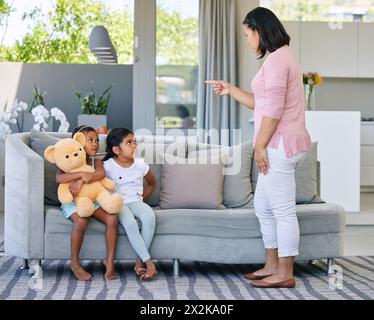 Mutter, zeigendes und schimpfendes Kind zu Hause, Disziplin und Kommunikation oder strenge Eltern im Familienhaus. Wohnzimmer, Mädchen und Sofa zur Bestrafung Stockfoto