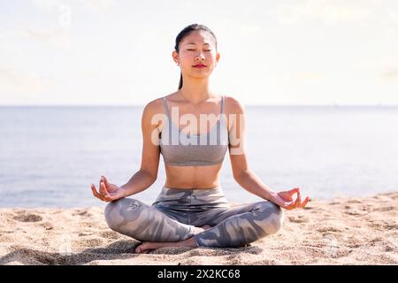 Junge asiatische Frau, die Meditation am Strand macht Stockfoto