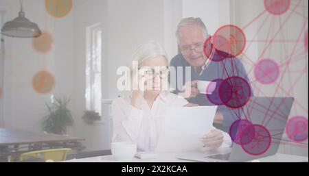 Bild der Mediensymbole über dem älteren kaukasischen Paar mit Laptop Stockfoto