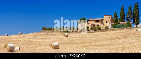 Montepulciano, Italien - 25. August 2013: Ländliche Landschaften der Toskana, Italien. Viele Rundballen und Heuhaufen auf den Feldern. Gemauertes Bauernhaus steht Stockfoto