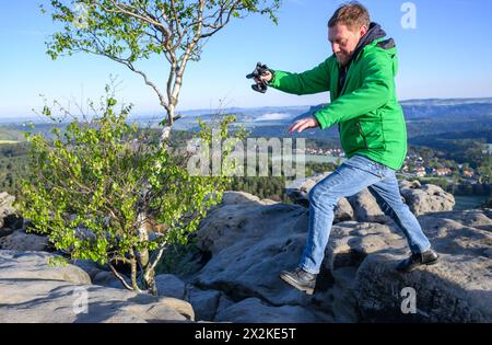 Gohrisch, Deutschland. April 2024. Michael Kretschmer (CDU), sächsischer Ministerpräsident, springt bei einer Wanderung vor der Sächsischen Kabinettssitzung im Bezirk Sächsische Schweiz-Osterzgebirge über einen Stein auf dem Tafelberg Gohrisch. Robert Michael/dpa/Alamy Live News Stockfoto