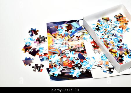 Auf weißem Hintergrund befinden sich Puzzles, die von der Box verstreut sind, und ein Bild mit Anweisungen zum Erstellen einer bunten Leinwand. Stockfoto