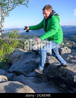 Gohrisch, Deutschland. April 2024. Michael Kretschmer (CDU), sächsischer Ministerpräsident, springt bei einer Wanderung vor der Sächsischen Kabinettssitzung im Bezirk Sächsische Schweiz-Osterzgebirge über einen Stein auf dem Tafelberg Gohrisch. Robert Michael/dpa/Alamy Live News Stockfoto