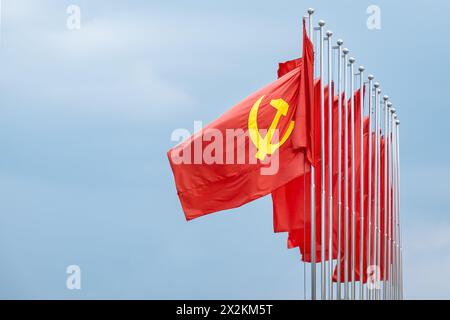Große kommunistische Flagge, die im Wind schwimmt, mit blauem Himmel Hintergrund. Rote sowjetische Flagge winkt am windigen Tag in Asien, Vietnam Stockfoto