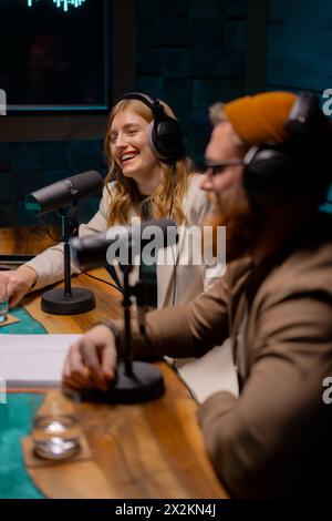 Mann und Frau sitzen vor Mikrofonen in einem Studio. Podcast-Studio-Konzept Stockfoto