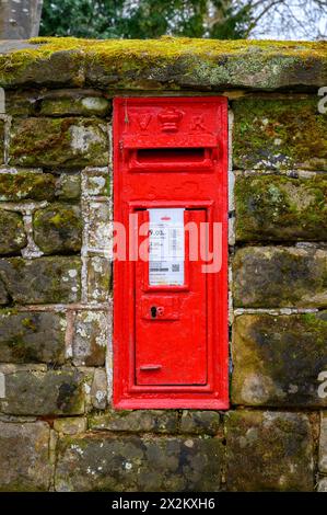 Ein viktorianischer roter Briefkasten in einer Steinmauer in der historischen Marktstadt Horsham, West Sussex, England. Stockfoto