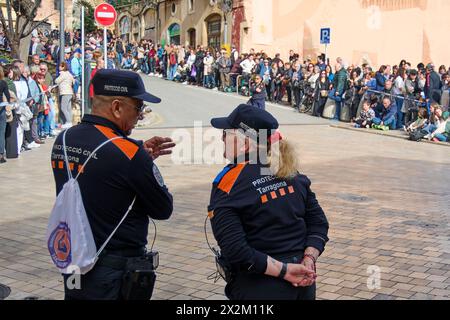 Tarragona, Spanien - 23. April 2024: Zwei nach hinten gerichtete Katastrophenschutzbeamte beobachten während einer Veranstaltung im Freien auf einer belebten Straße eine Menschenmenge und sorgen für Sicherheit Stockfoto