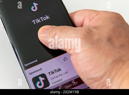 London. UK- 04.18.2024. Eine Hand, die ein Mobiltelefon hält und auf dem Bildschirm den TikTok-Namen und das Logo der Social-Media-Anwendung zur Videofreigabe anzeigt. Stockfoto