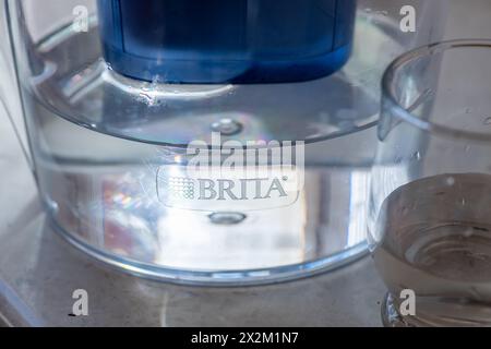 London. UK- 04.17.2024. Eine Brita Wasserfilterkanne und ein Glas Wasser mit Sonnenlicht, die den Markennamen und das Logo hervorheben. Stockfoto