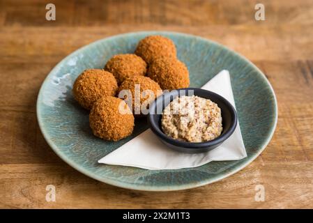 Nahaufnahme traditioneller niederländischer Bitterballen mit Senf auf einem Teller auf einem Holztisch Stockfoto