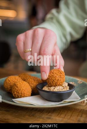 Nahaufnahme traditioneller niederländischer Bitterballen, die in einem Café-Restaurant in Senf getaucht werden Stockfoto