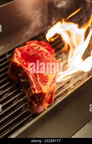 Steakküche in der Restaurantküche mit Flammen und Rauch Stockfoto