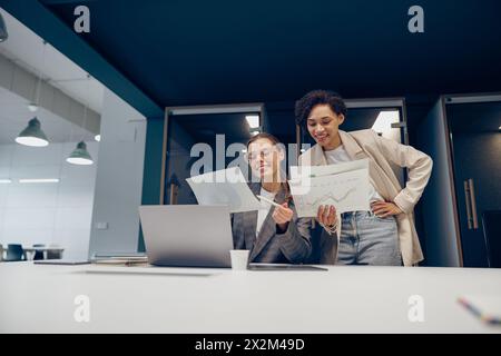 Zwei weibliche Experten für professionelle Führungskräfte diskutieren über die Zusammenarbeit mit Finanzbuchhaltungsunterlagen Stockfoto