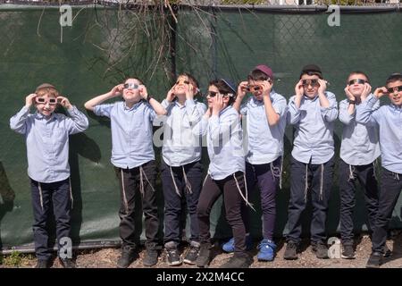 Eine Gruppe orthodoxer jüdischer Jungen beobachten die Sonnenfinsternis 2024 vom Schulhof ihrer Jeschiwa aus. Im Rockland County, New York. Stockfoto