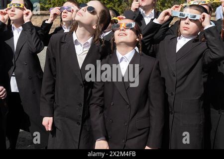 Eine Gruppe orthodoxer jüdischer Jeschiwa-Schüler mit langem Peyus beobachten die Sonnenfinsternis von 2024 auf ihrem Schulhof. Im Rockland County, New York. Stockfoto