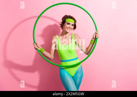 Foto-Porträt der schönen jungen Dame Halten Hooahoop Mode Modell gekleidet stilvolle grüne Sport Jumpsuit isoliert auf rosa Farbe Hintergrund Stockfoto