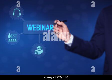 Webinar. Geschäftsmann mit virtuellem Bildschirm mit Symbolen auf blauem Hintergrund, Nahaufnahme Stockfoto