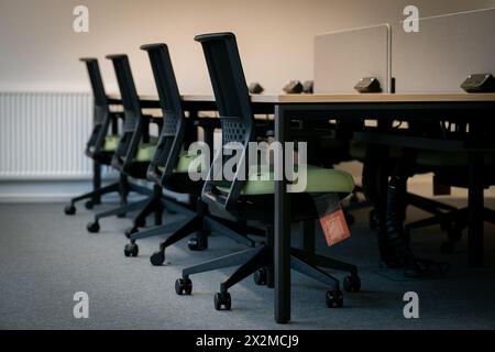 Eine Reihe schwarzer ergonomischer Bürostühle vor Schreibtischen mit Computern in einem modernen Arbeitsbereich mit neutraler Farbpalette Stockfoto