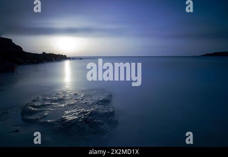 Langzeitaufnahme, die die ruhige Dämmerung am Playa de los Roques mit seidenglattem Wasser und einem sanften Sonnenuntergang festnimmt. Stockfoto