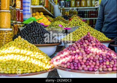 Ein lebhaftes Foto mit verschiedenen Arten konservierter Oliven, ein Grundnahrungsmittel der marokkanischen Küche, zum Verkauf in einem traditionellen Marktumfeld. Stockfoto