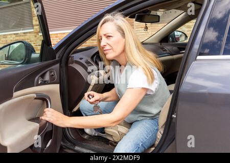 Frau mit besorgtem Ausdruck, die aus einem Auto mit Autoschlüsseln steigt Stockfoto