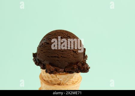 Eine Schaufel Schokoladeneis in einem Waffelkegel auf grünem Hintergrund Stockfoto