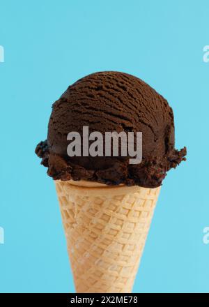 Eine Schaufel Schokoladeneis in einem Waffelkegel auf blauem Hintergrund Stockfoto