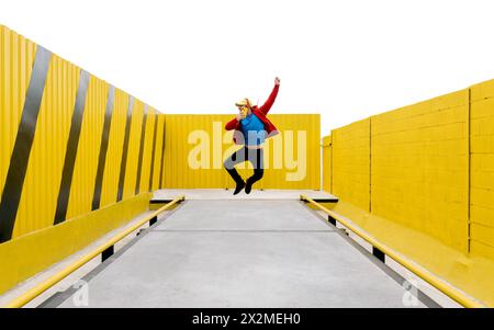 Person im dynamischen Mittelsprung vor einem auffälligen gelben geometrischen Hintergrund mit Kontraststreifen Stockfoto