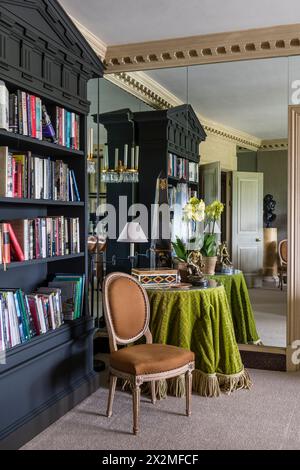 Lindgrüne Tischdecke und Bücherregal spiegeln sich in der Spiegelwand, Apartment Chelsea, London, Großbritannien Stockfoto