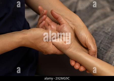 Latina-Frau, die auf dem Rücken liegt und eine ayurvedische Massage in ihren Händen erhält Stockfoto