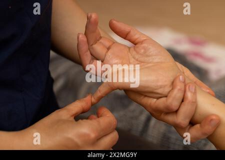 Latina-Frau, die auf dem Rücken liegt und eine ayurvedische Massage in ihren Händen erhält Stockfoto