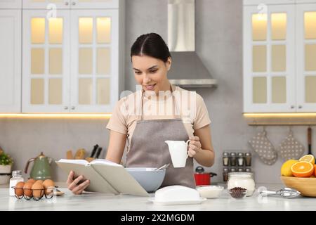 Junge Frau mit Rezeptbuch Kochen in der Küche Stockfoto