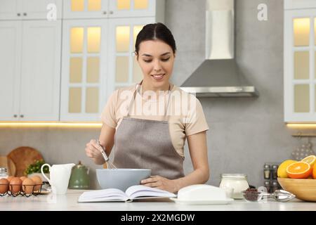 Junge Frau mit Rezeptbuch Kochen in der Küche Stockfoto
