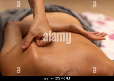 Latina-Frau, die auf dem Rücken liegt und eine ayurvedische Rückenmassage erhält Stockfoto