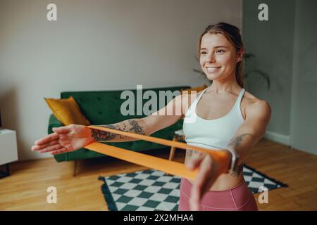 Junge Frauenübungen mit Widerstandsband im Wohnzimmer Stockfoto