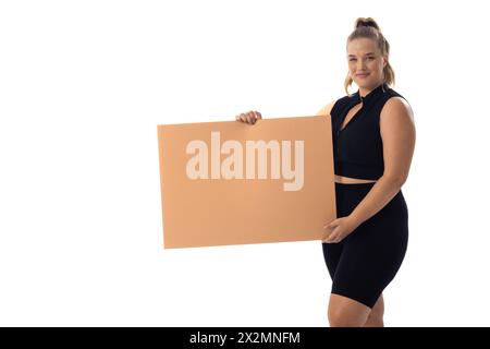 Weiße Frau in schwarzem Kleid in Übergröße hält ein leeres Schild auf weißem Hintergrund Stockfoto