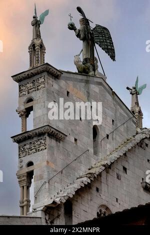 Geflügelte Statue des heiligen Michael, der Drachen auf dem Giebel der pisanisch-romanischen Fassade der Chiesa di San Michele in Foro in Lucca, Toskana, Italien. Die Kirche wurde 1070 auf Befehl von Papst Alexander II. Erbaut, die Fassade wurde in den 1200er Jahren hinzugefügt Stockfoto