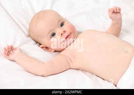 Süßes kleines Baby mit allergischer Rötung auf den Wangen, die auf weißer Decke liegen Stockfoto