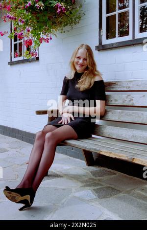 Junge lächelnde, hübsche, natürliche blonde Frau saß vor dem Red Lion Pub chalton hampshire england 1990er Jahre Stockfoto
