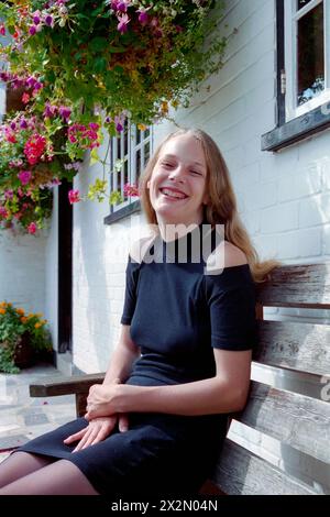 Junge lächelnde, hübsche, natürliche blonde Frau saß vor dem Red Lion Pub chalton hampshire england 1990er Jahre Stockfoto