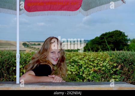 Junge lächelnde, hübsche, natürliche blonde Frau saß im Garten im Red Lion Pub chalton hampshire england 1990er Jahre Stockfoto