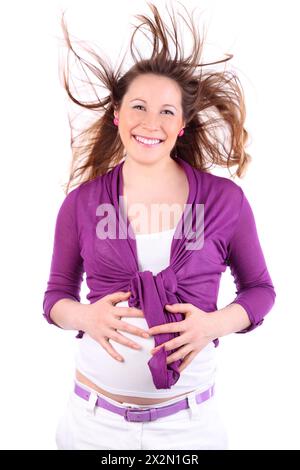 Junge schwangere Frau steht im Wind und hält den Magen isoliert auf weißem Hintergrund. Stockfoto